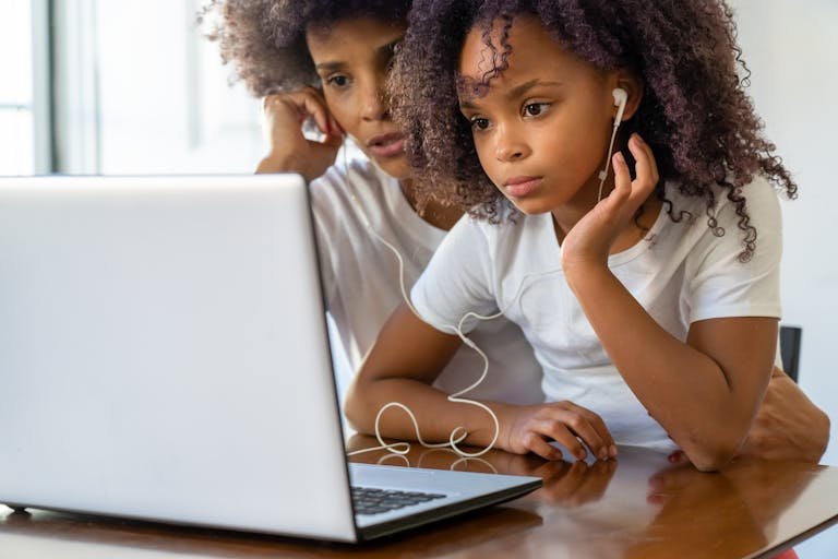 African American mother and daughter using a laptop together indoors, bonding and learning.