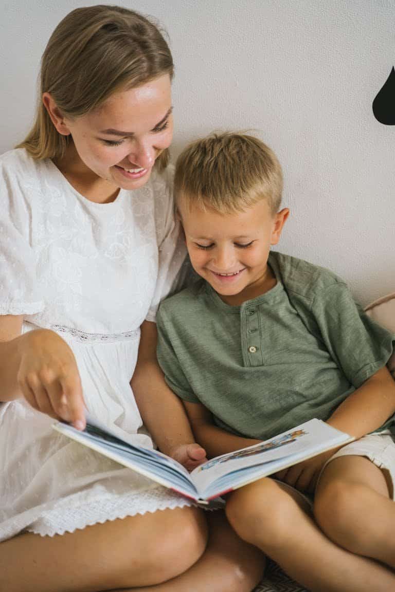 A mother and son sharing a joyful moment reading a book indoors, exuding warmth and togetherness.